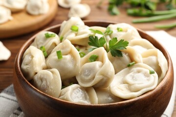 Delicious dumplings with fresh green onion and parsley on table, closeup