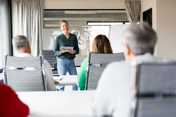 Happy businesswoman discussing ideas with coworkers in office workshop