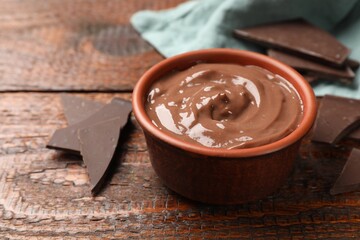 Tasty pudding and pieces of chocolate on wooden table, closeup