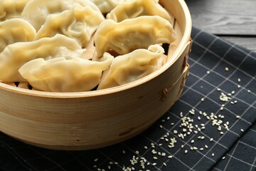 Tasty boiled gyoza (dumplings) with sesame on black table, closeup