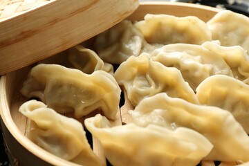Tasty boiled gyoza (dumplings) in bamboo steamer on table, closeup