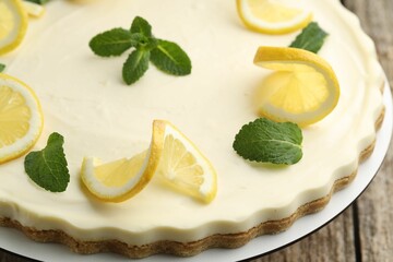 Delicious lemon cheesecake with mint on wooden table, closeup