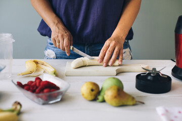 Woman cutting banana for a smoothie