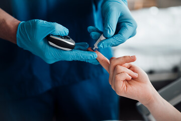 Doctor performing a blood sugar test on a patient in a clinic