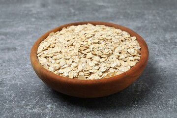 Composition with oatmeal flakes on gray background. Cooking breakfast
