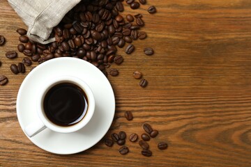 Cup of coffee with fresh coffee beans on wooden background