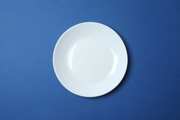 White empty plate with cutlery on a colored background