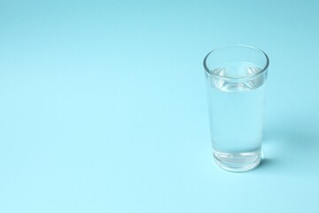 Transparent glass with water on blue background. Drinking clear water in the morning for health