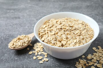 Composition with oatmeal flakes on gray background. Cooking breakfast