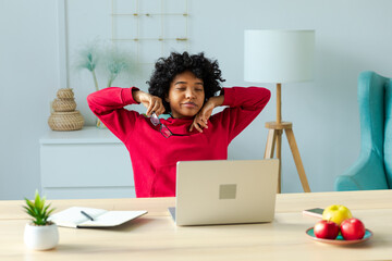 African american girl at home office relaxing stretching hands and body taking break from work on...