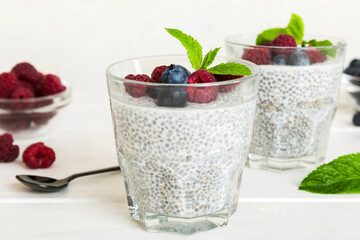 Healthy breakfast or morning with chia seeds vanilla pudding raspberry and blueberry berries on table background, vegetarian food, diet and health concept. Chia pudding with raspberry and blueberry