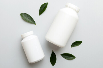 supplement pills with medicine bottle health care and medical top view. Vitamin tablets. Top view mockup bottle for pills and vitamins with green leaves, natural organic bio supplement, copy space