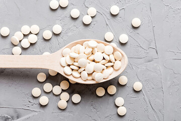 Heap of white pills on colored background. Tablets scattered on a table. Pile of red soft gelatin capsule. Vitamins and dietary supplements concept