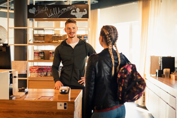 Coach talking to young woman at front desk of a gym