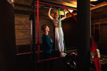 Young woman exercising in fitness gym with personal trainer