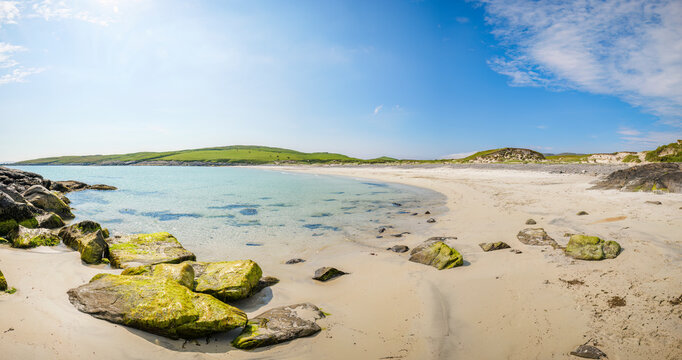 Scenic view of Bagh A'Deas beach on the Isle of Vatersay, Scotland with clear water and blue sky.