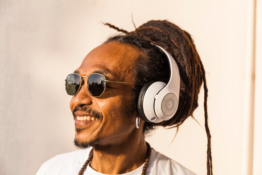 Portrait of mature man with dreadlocks and headphones, listening music and looking sideways