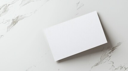 Blank white business card on marble surface for branding and design presentation. Minimalistic and professional.