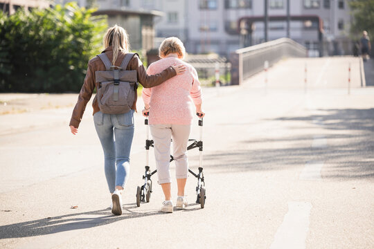Granddaughter assisting her grandmother walking with wheeled walker