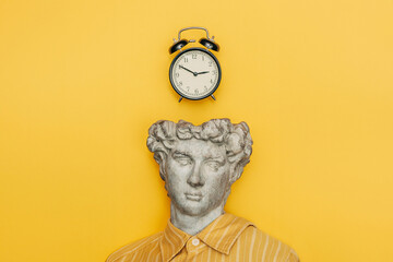 Classical bust with alarm clock on yellow background symbolizing time and urgency