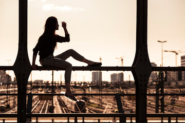 Young woman sitting on Hacker bridge at sunset, Munich, Germany