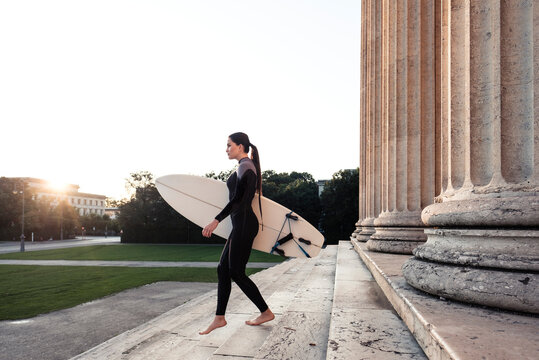 Young woman with surfboard on the way to Eisbach, Munich, Germany
