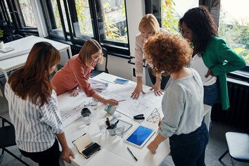 Businesswomen having a meeting in office with blueprints on table