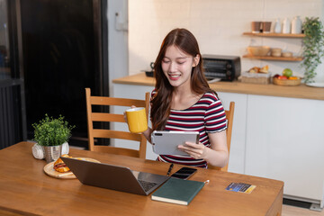 Lifestyle people, using laptop computer and Tablet and enjoys a coffee sitting in the kitchen.