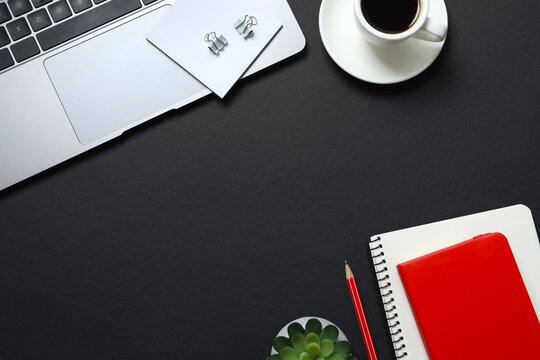 Business concept. Top view photo of workplace with planner, pencil, coffee cup and laptop on black background with blank space