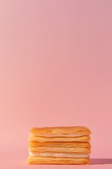 Stack of golden pancakes on pastel pink background creates invit
