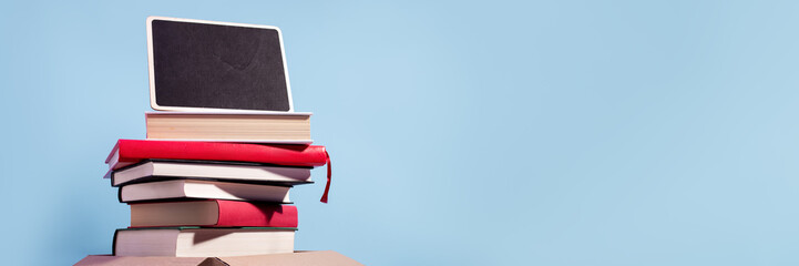 Books in a box ready for donation on blue with empty sign for text, copy space. Concept of books donations