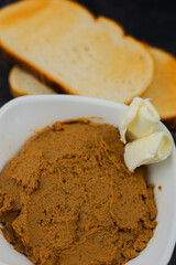 Close-up of a plate of liver pate with slices of butter on a background of wheat bread toast. The concept of snacks, meat and healthy food. High quality photo