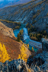 Autumn scene featuring a winding river amidst rocky mountain landscape and golden foliage. Vibrant natural beauty with serene atmosphere. Perfect depiction of wilderness and calm river view.