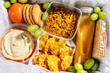 Ready prepared brunch box with quinoa salad, gluten free nuggets and fresh smoothie, top view