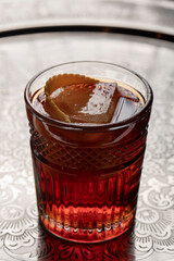 alcoholic cocktail in a glass with lemon, ice cubes on a silver tray.