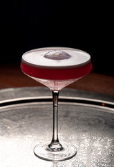 Cocktail in a martini glass on a dark background.