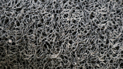 A textured, intricate, and tangled mesh pattern, showcasing a complex network of interwoven fibers.