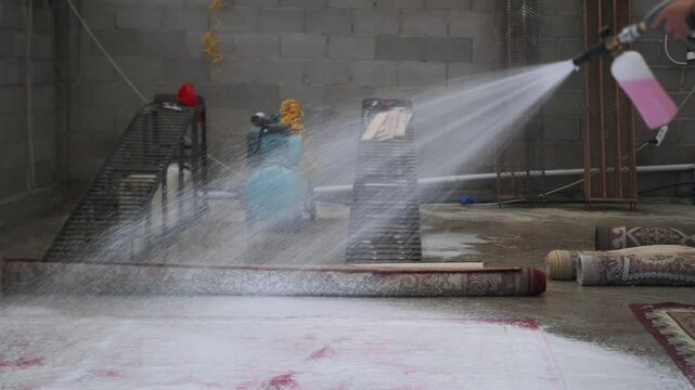 Spraying cleaning solution onto the carpet. A specialist operates a pneumatic sprayer, evenly applying active cleaning foam to penetrate deep into the fibers and remove dirt effectively.