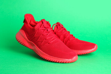 Pair of stylish red sneakers on green background
