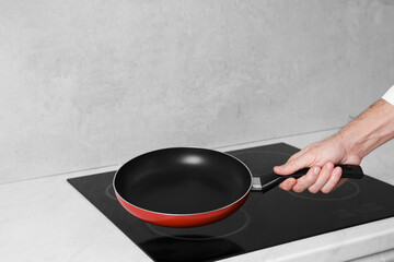 Chef holding frying pan over cooktop in kitchen, closeup