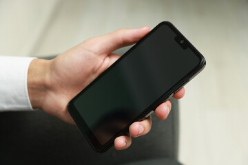 Man using smartphone with blank screen indoors, closeup