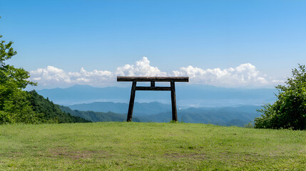 Wooden Torii Gate on Green Hilltop with Distant Mountain View