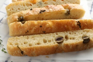 Slices of delicious focaccia bread with olives and thyme on table, closeup