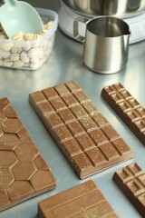 Different tasty Dubai chocolate bars with pistachios and knafeh on grey table