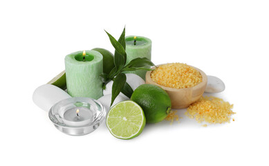 Spa composition with limes, massage stones, burning candles, sea salt and green leaves isolated on white