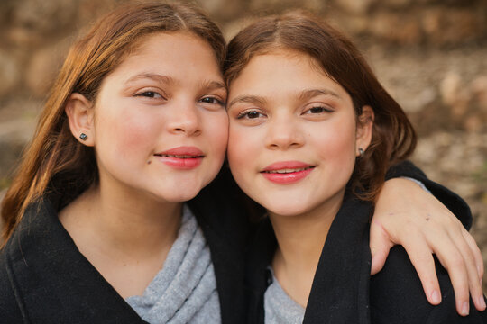 Portrait of smiling twin sisters embracing outdoors