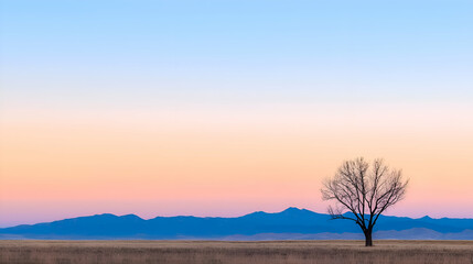 Solitary Tree Silhouette at Sunset Over Pastel Mountains