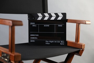 Director's chair with clapperboard on light grey background, closeup