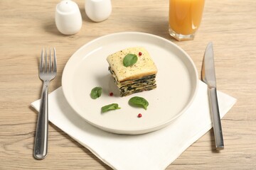 Piece of tasty spinach lasagna served on wooden table