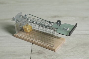Metal mouse trap with piece of cheese indoors, closeup